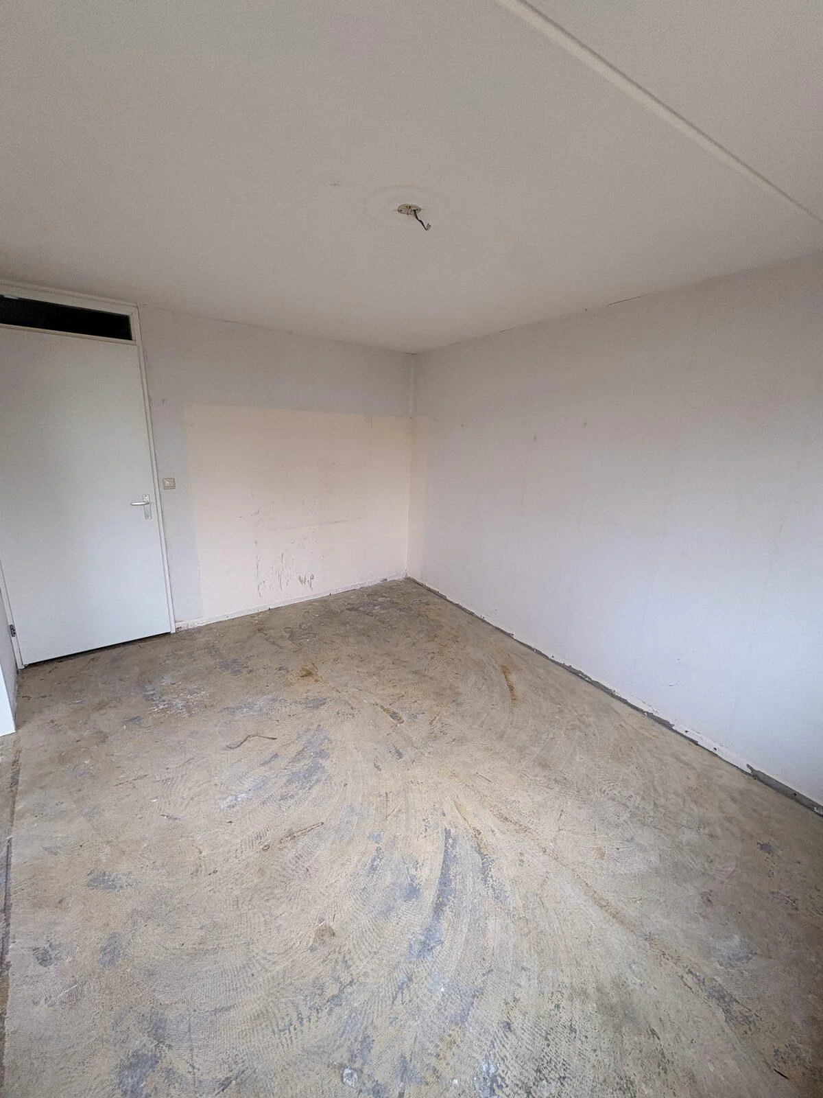 Woonkamer na oplevering, met verwijderd behang